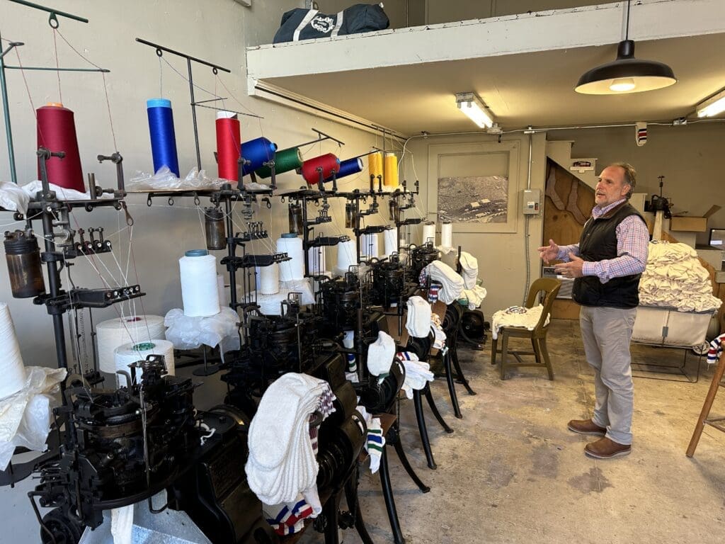 Man standing in front of vintage sock-knitting machines.
