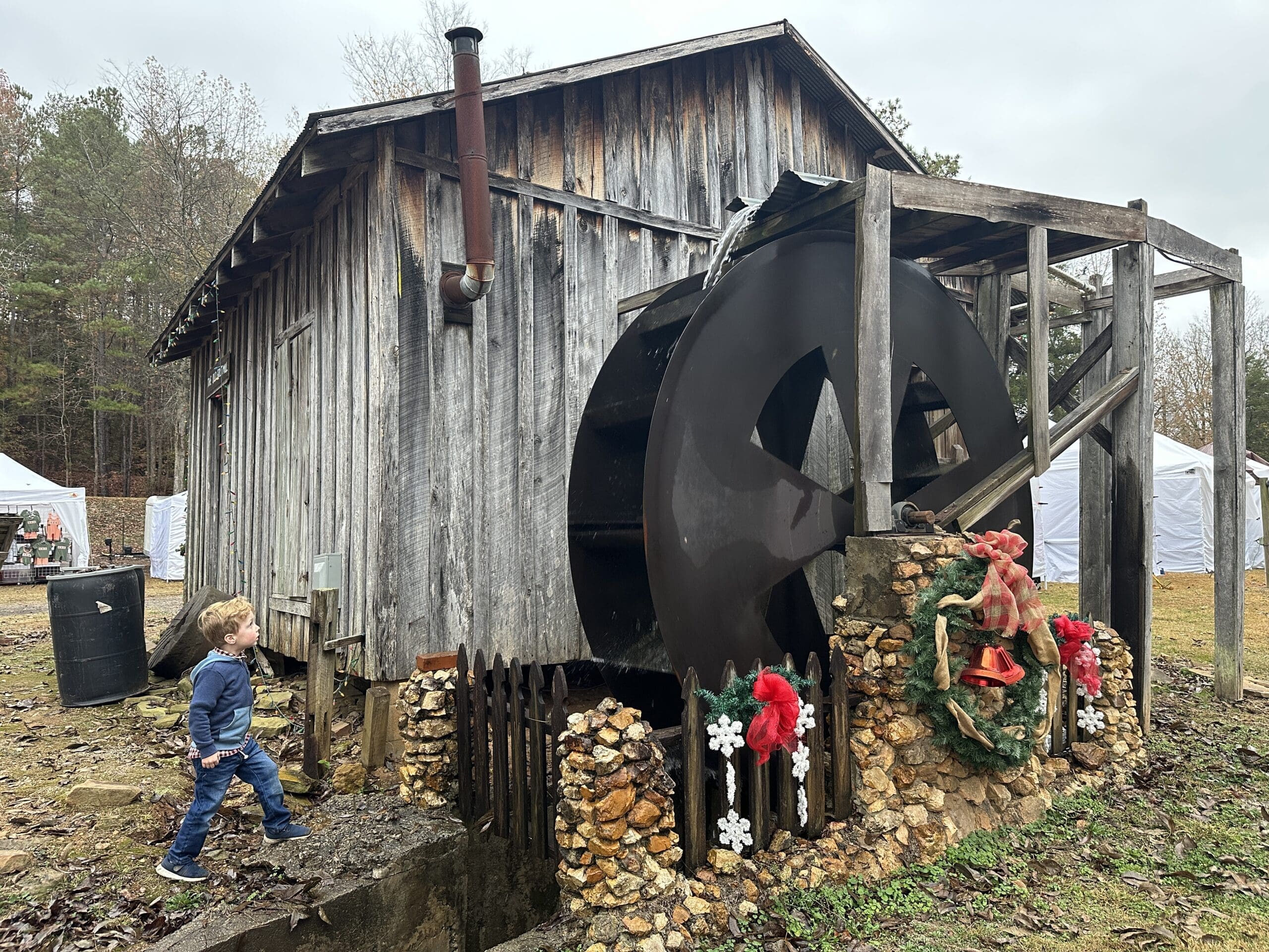 Child looking up at the wheel of a grist mill at Homestead Hollow.