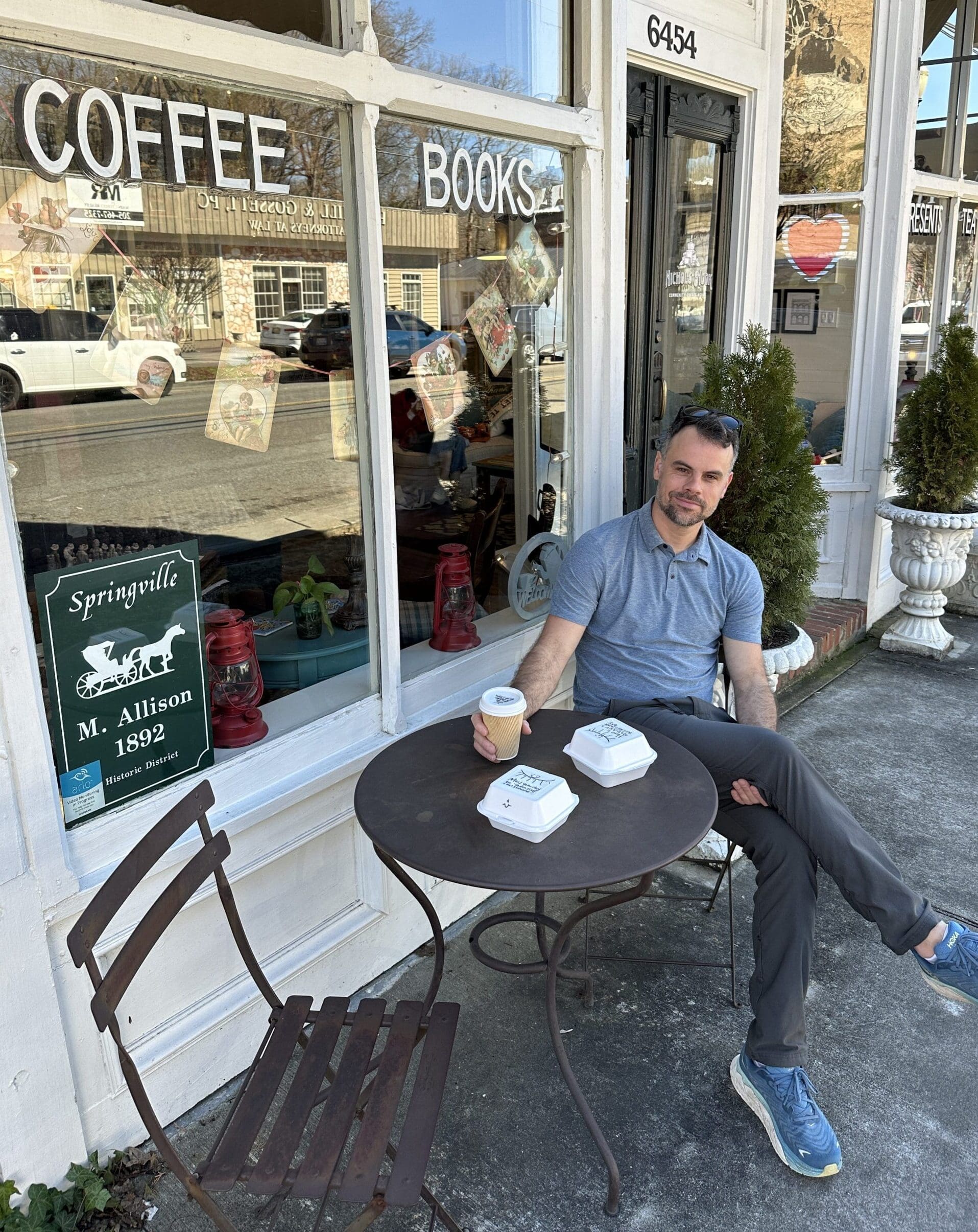 Man sitting in front of cafe with coffee.