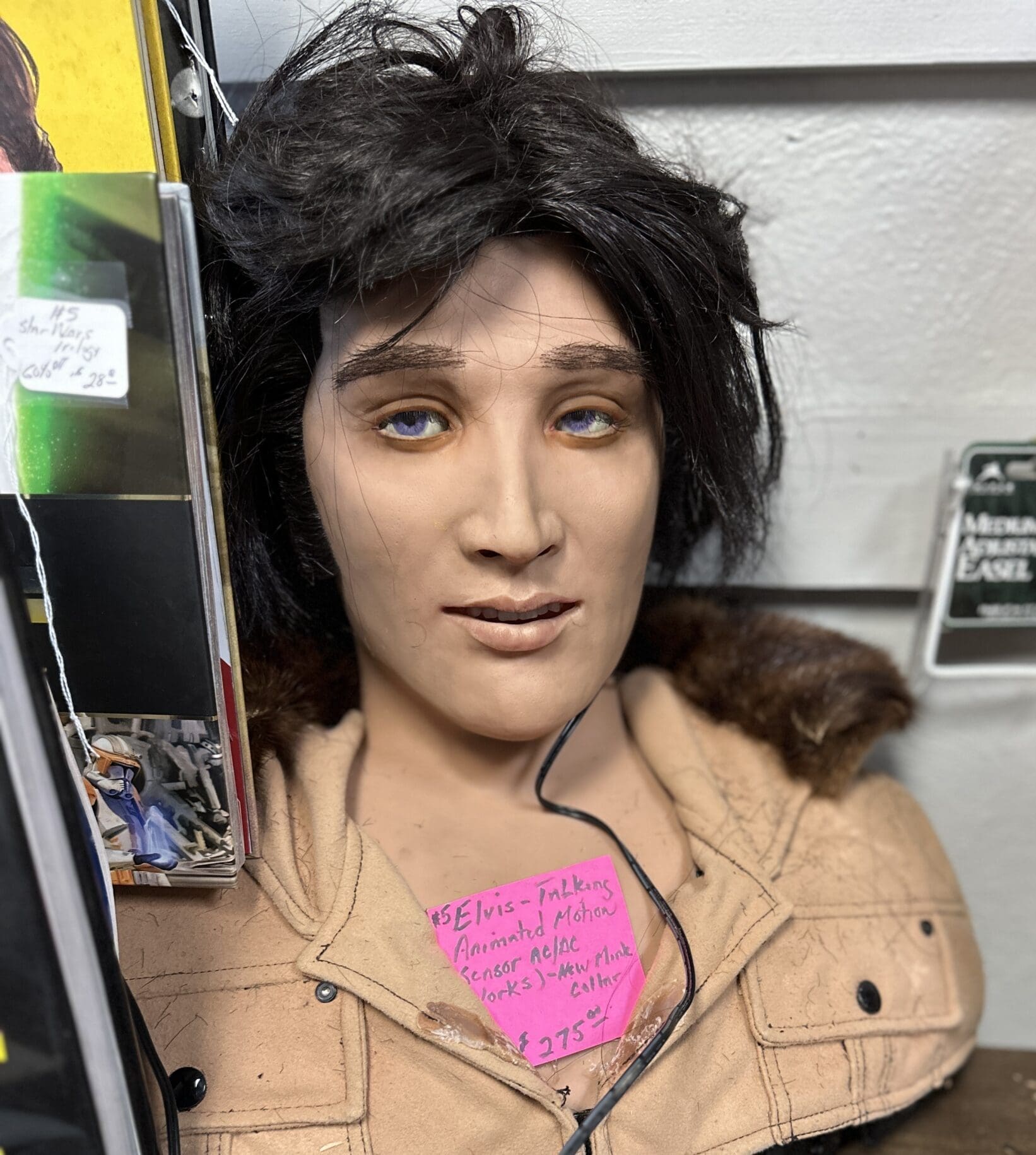Motion-activated, animatronic, singing Elvis memorabilia on antique store shelf.