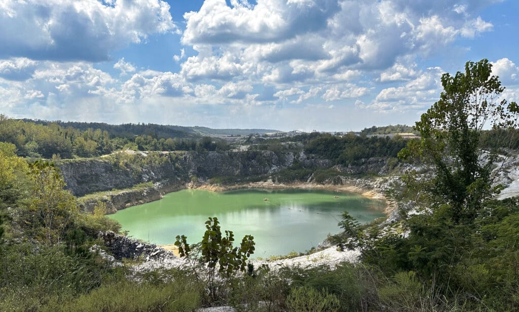 View into a large marble quarry filled with green water.