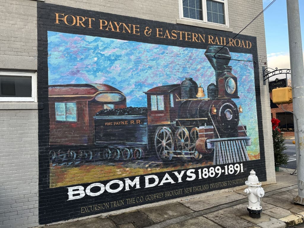 Mural of a steam train engine. Mural reads: Fort PAyne & Eastern Railroad. Boom Days (1889-1891)