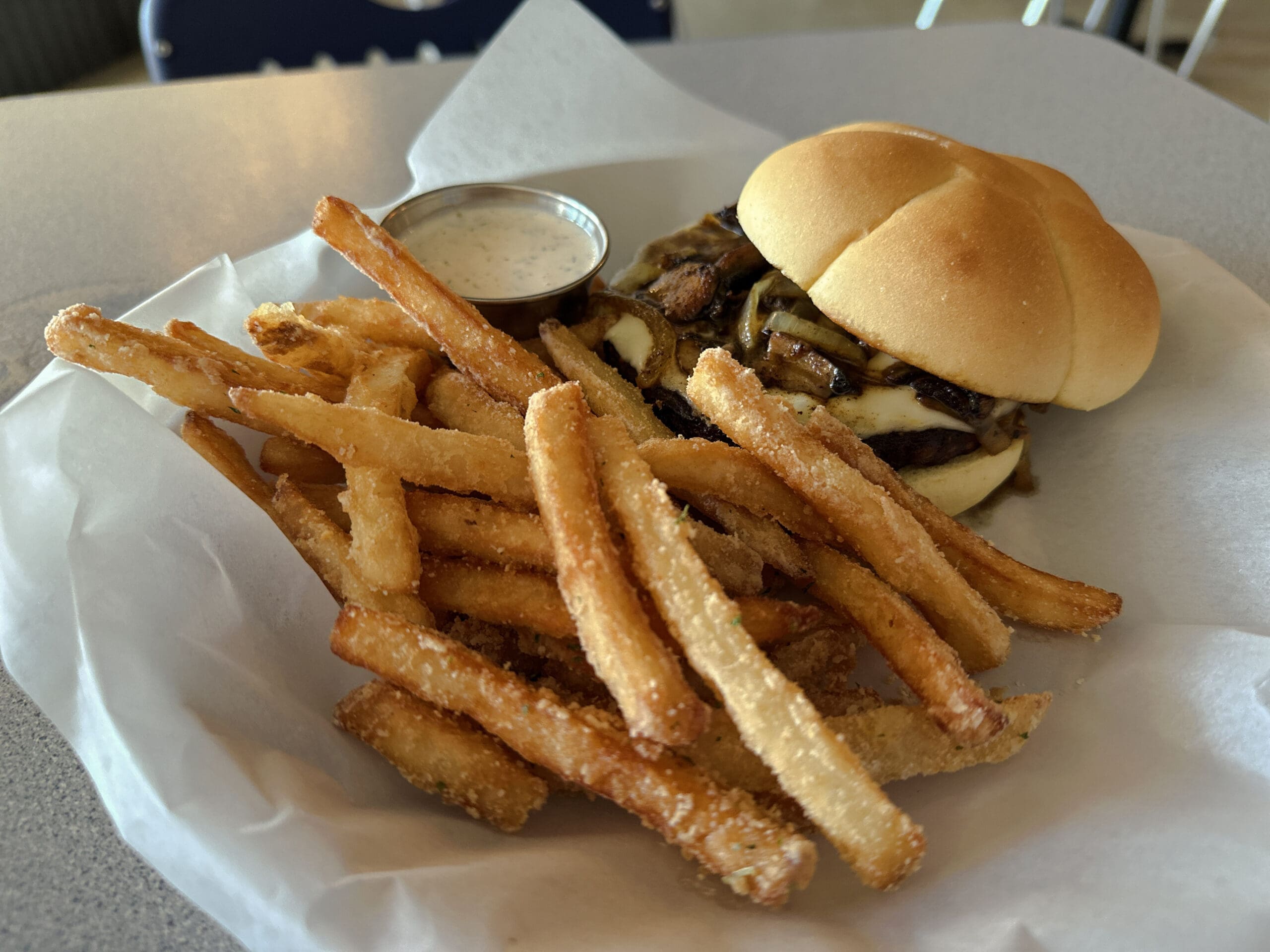Close-up photo of fries, dressing and a Swiss and mushroom veggie burger.