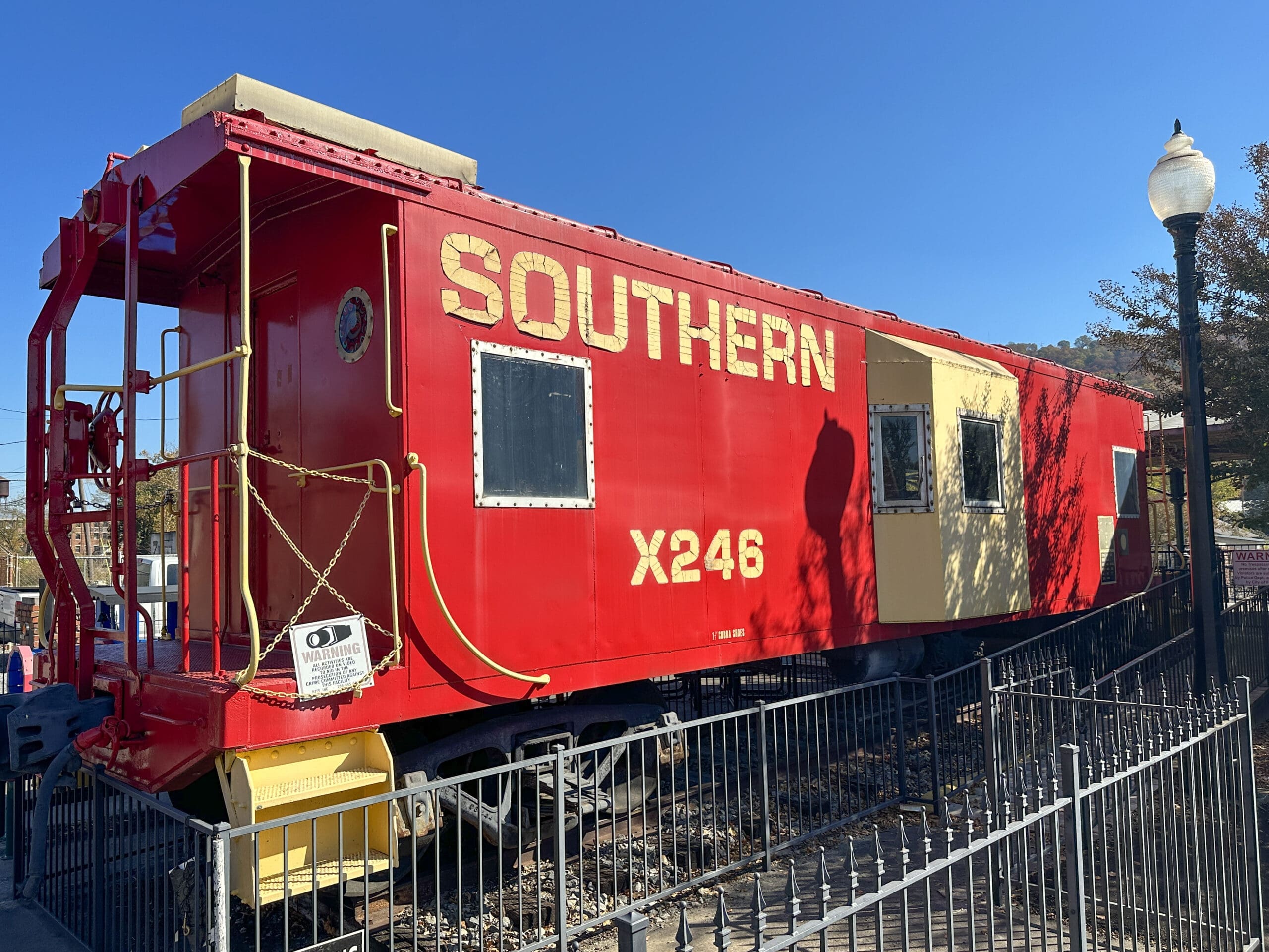 A red caboose behind a fence. Caboose features "Southern" painted in large yellow lettering.