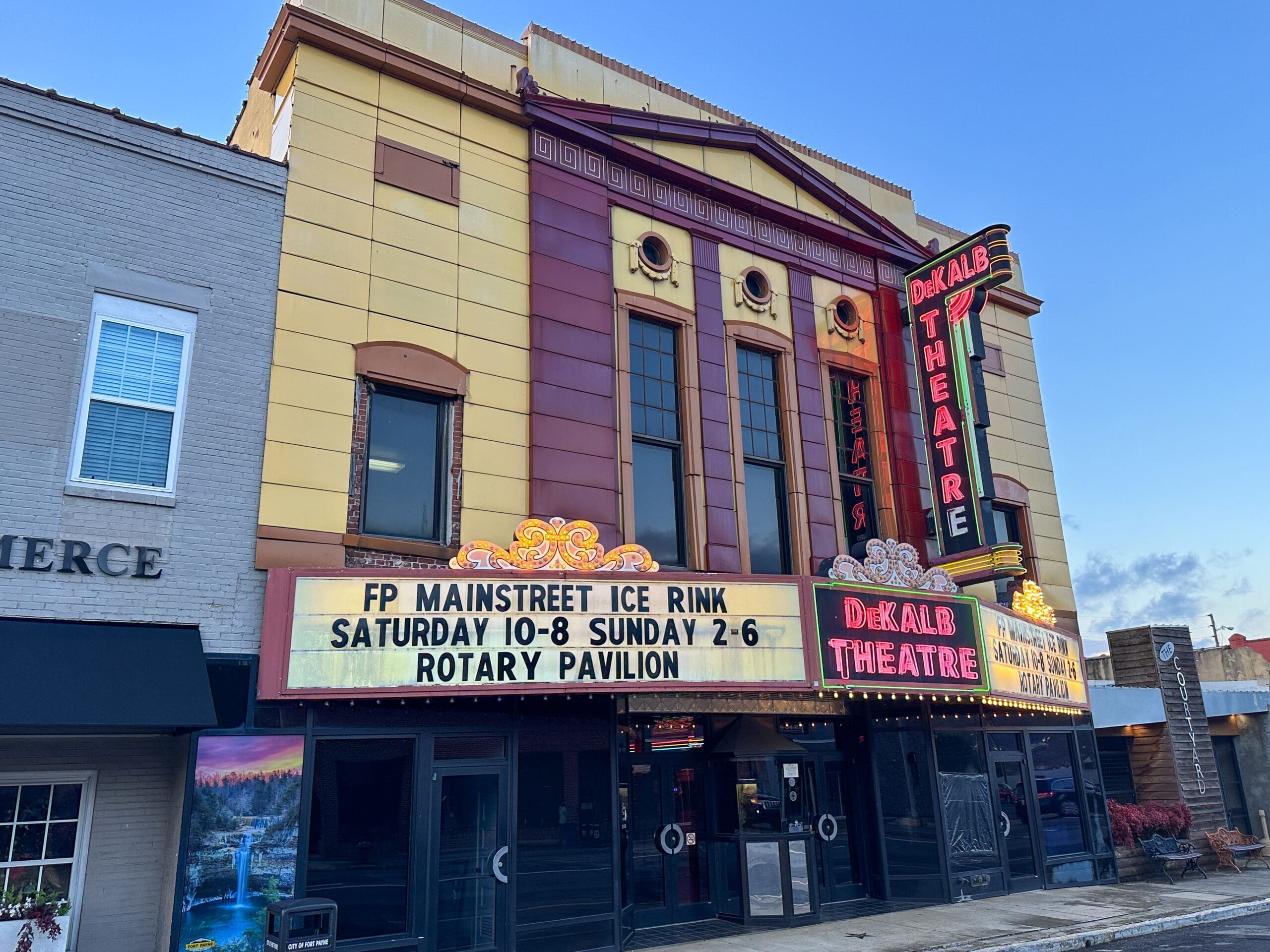 A historic theatre with neon signs reading "DeKalb Theatre".