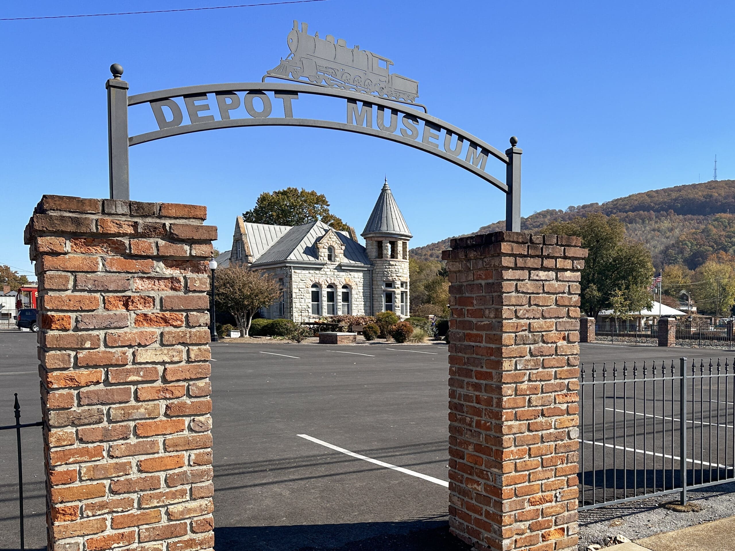Background: a scenic, historic train depot made of stone.
Foreground: an archway with a sign above reading "Depot Museum".