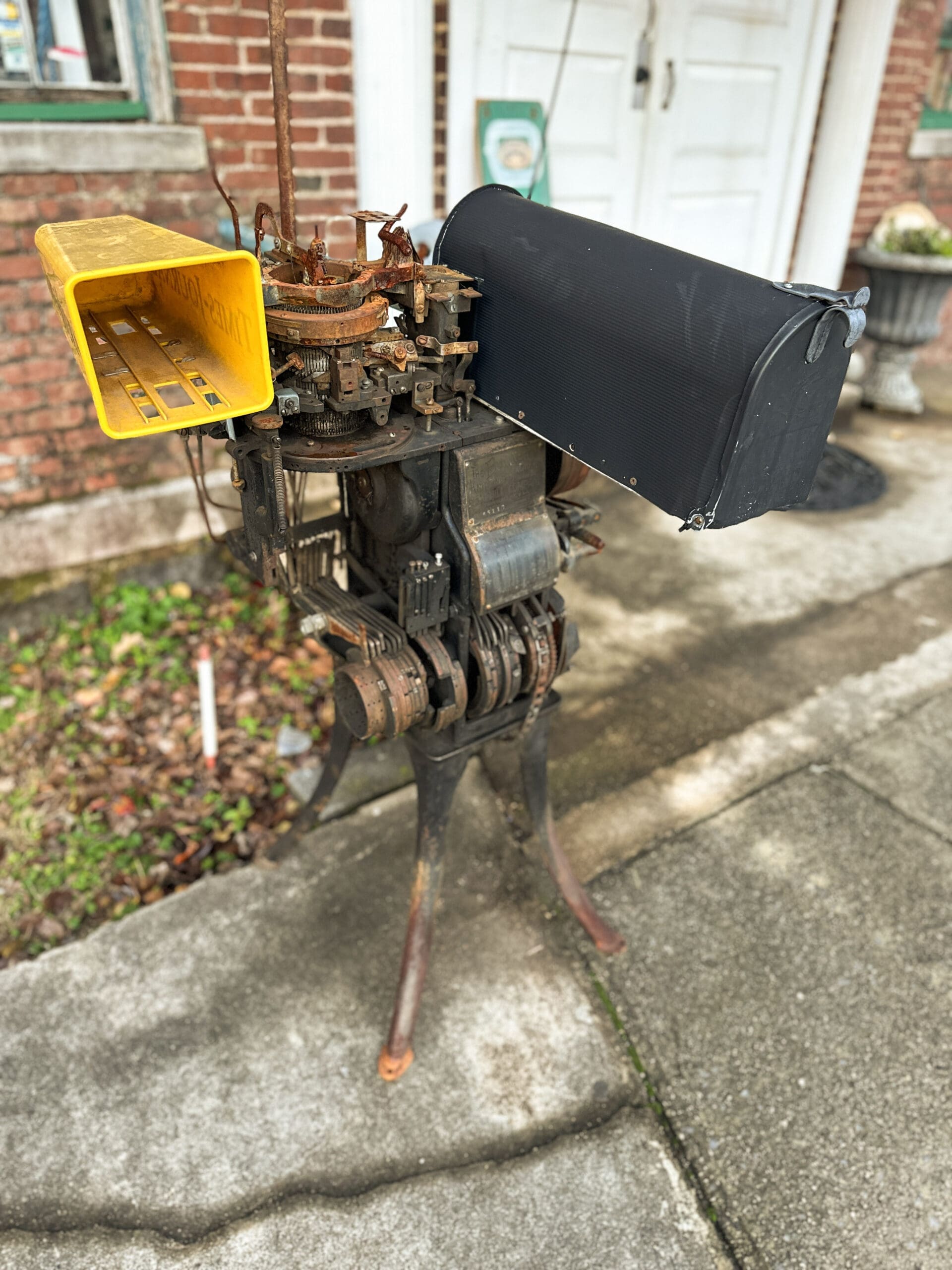 A mid-20th century, pre-digital sock knitting machine made to hold a mailbox.