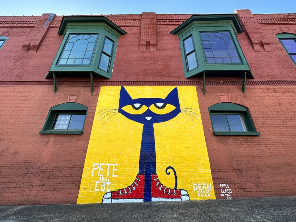 A one-story mural of children's book character Pete the Cat, a blue comic cat with large yellow eyes and red shoes.