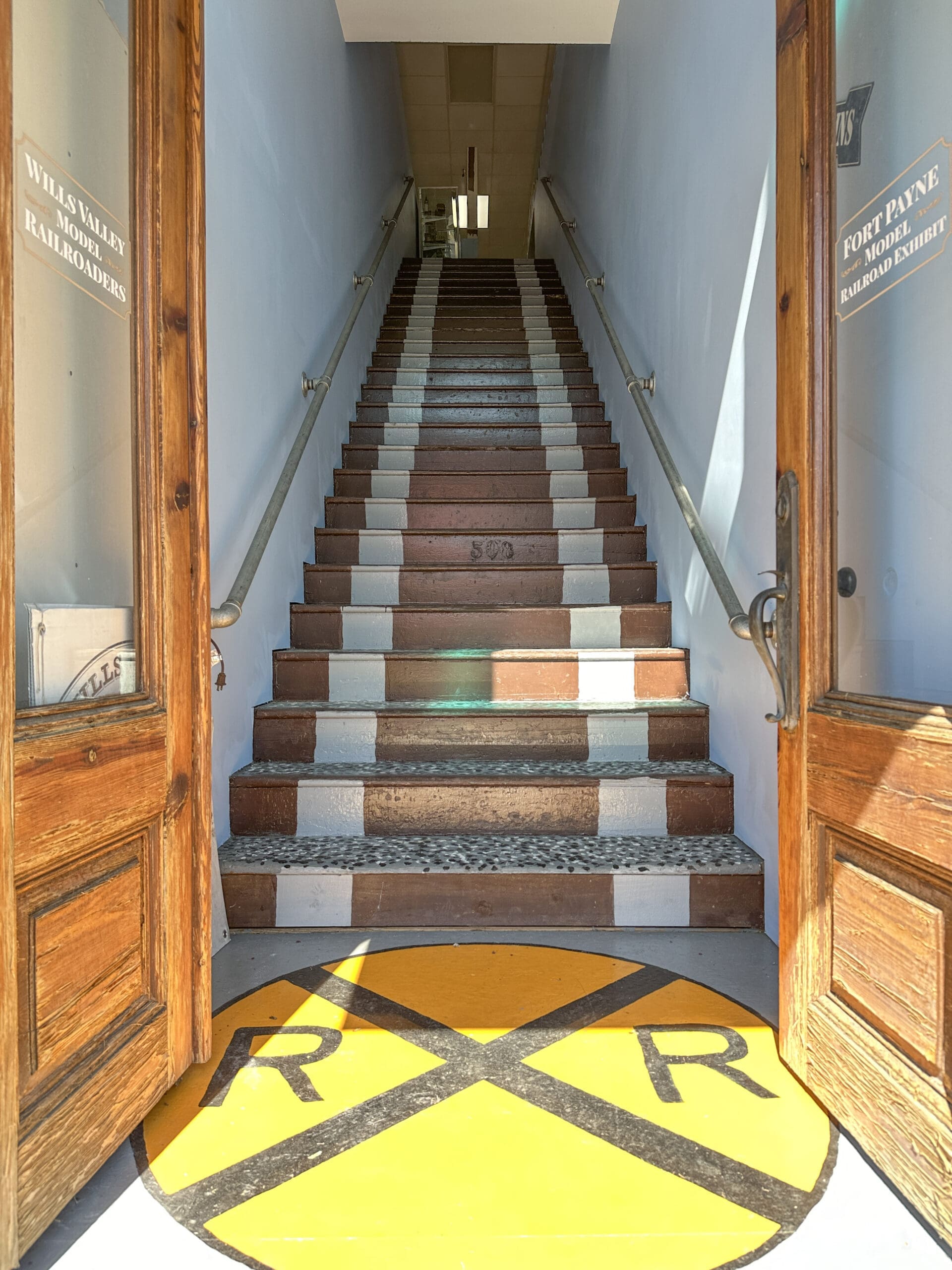 Doors open leading to a large staircase going upward. A big "RxR" railroad sign is painted on the ground at the bottom of the stairs.