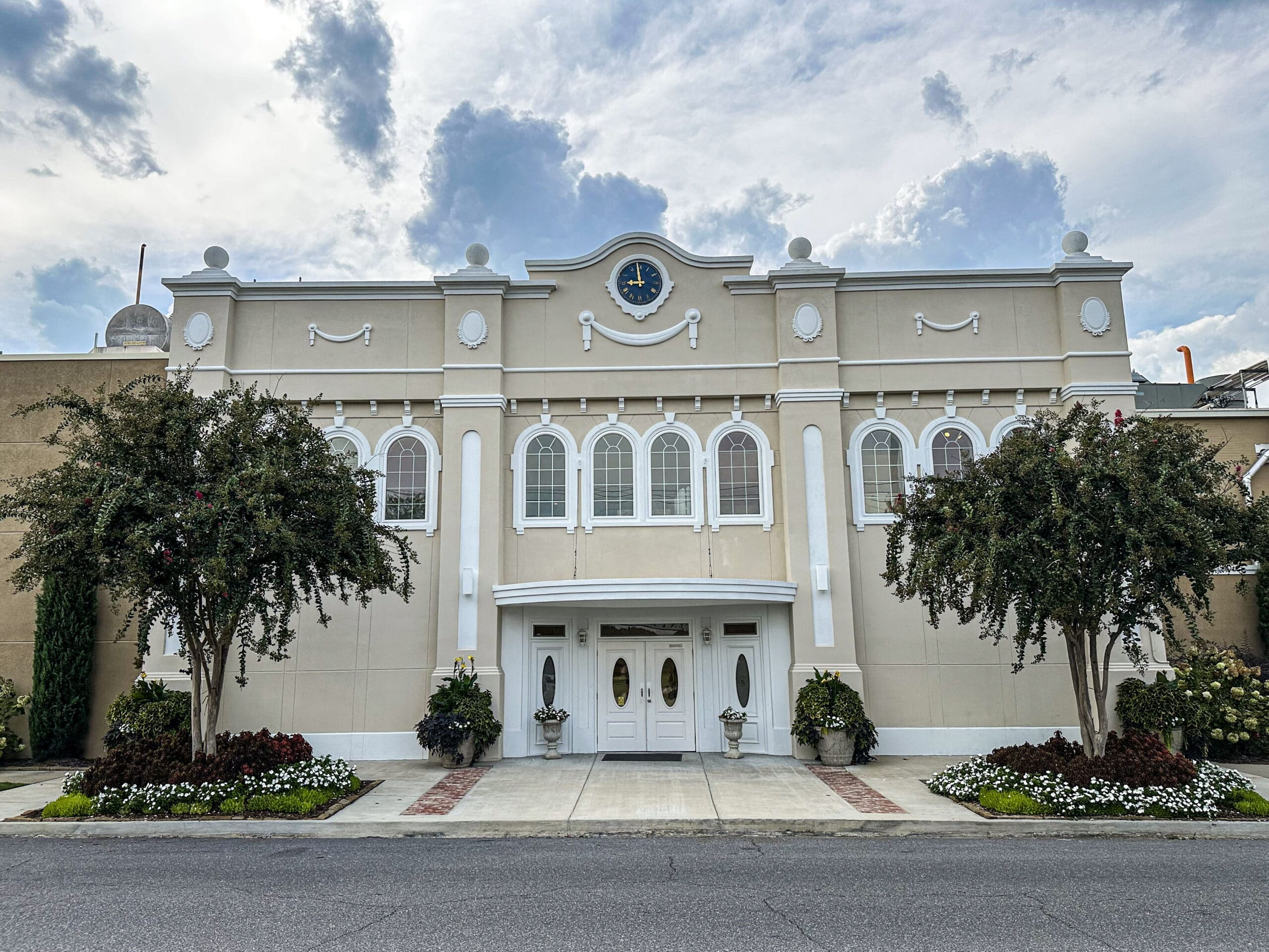 The two-story front of the Blue Bell Ice Cream factory store in Sylacauga. A crepe myrtle stands to each side of the doors.