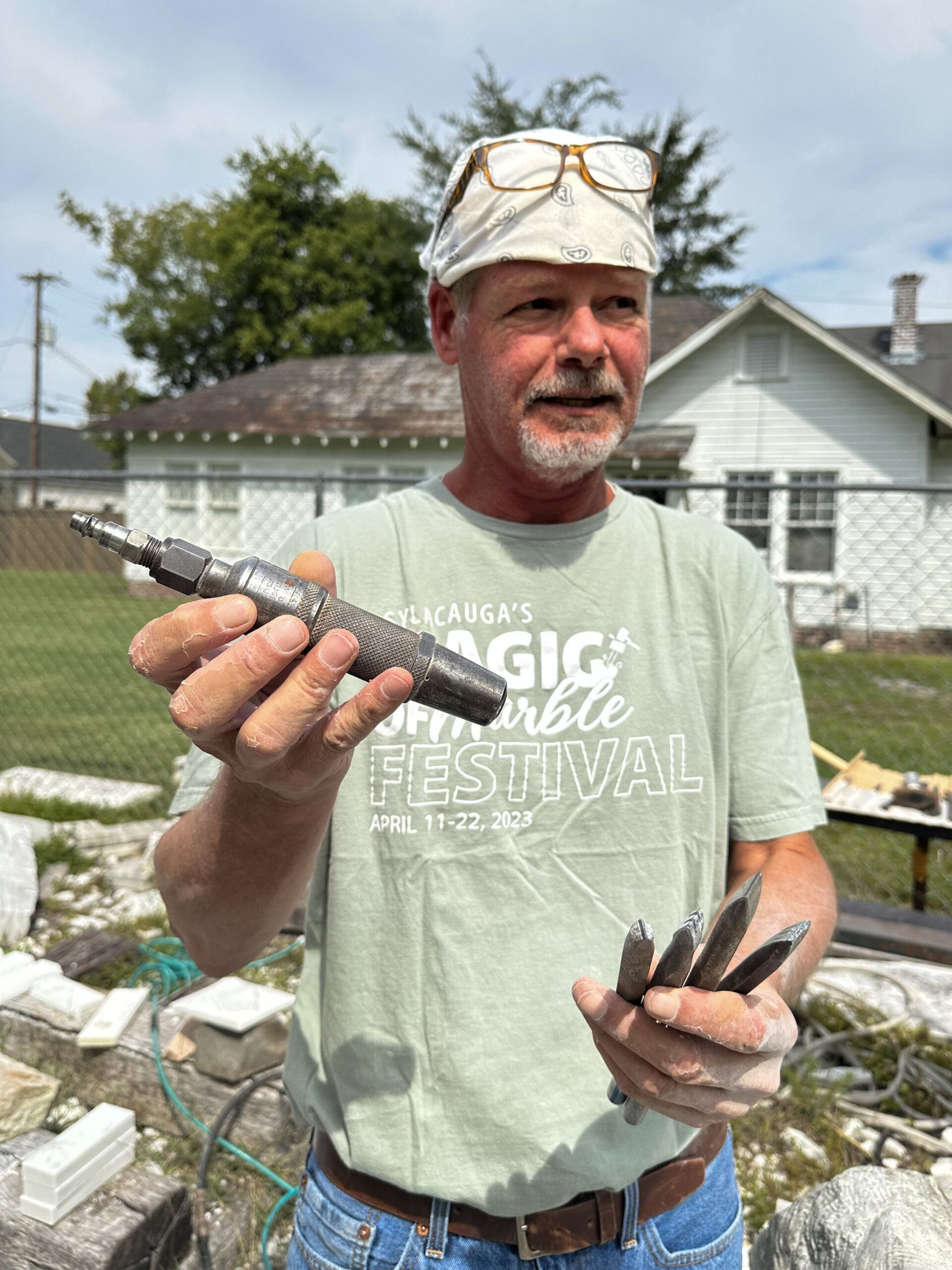 A man holds a drill bilt for sculpting marble.
