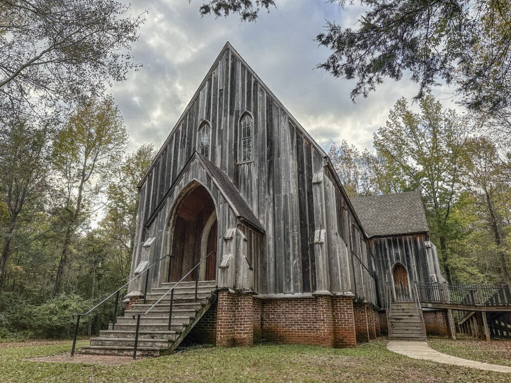 An old, wooden Gothic Revival church surrounded by trees.